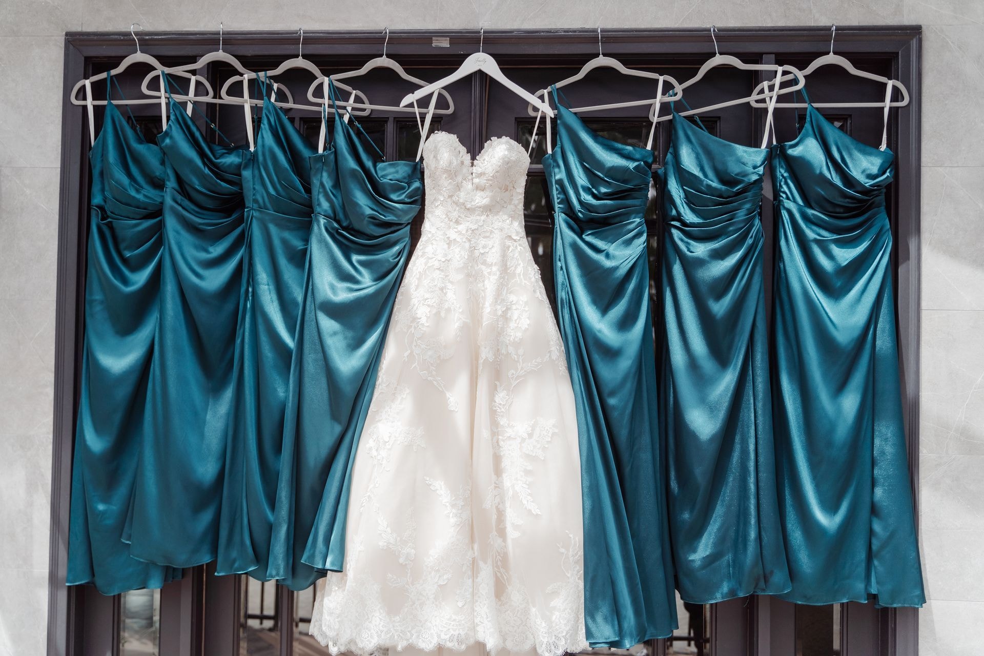 Teal bridesmaid dresses displayed alongside a white wedding gown