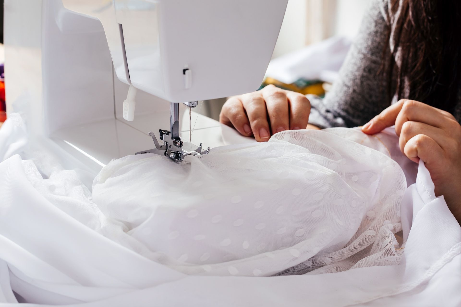 Sewing machine and hands working on bridal fabric