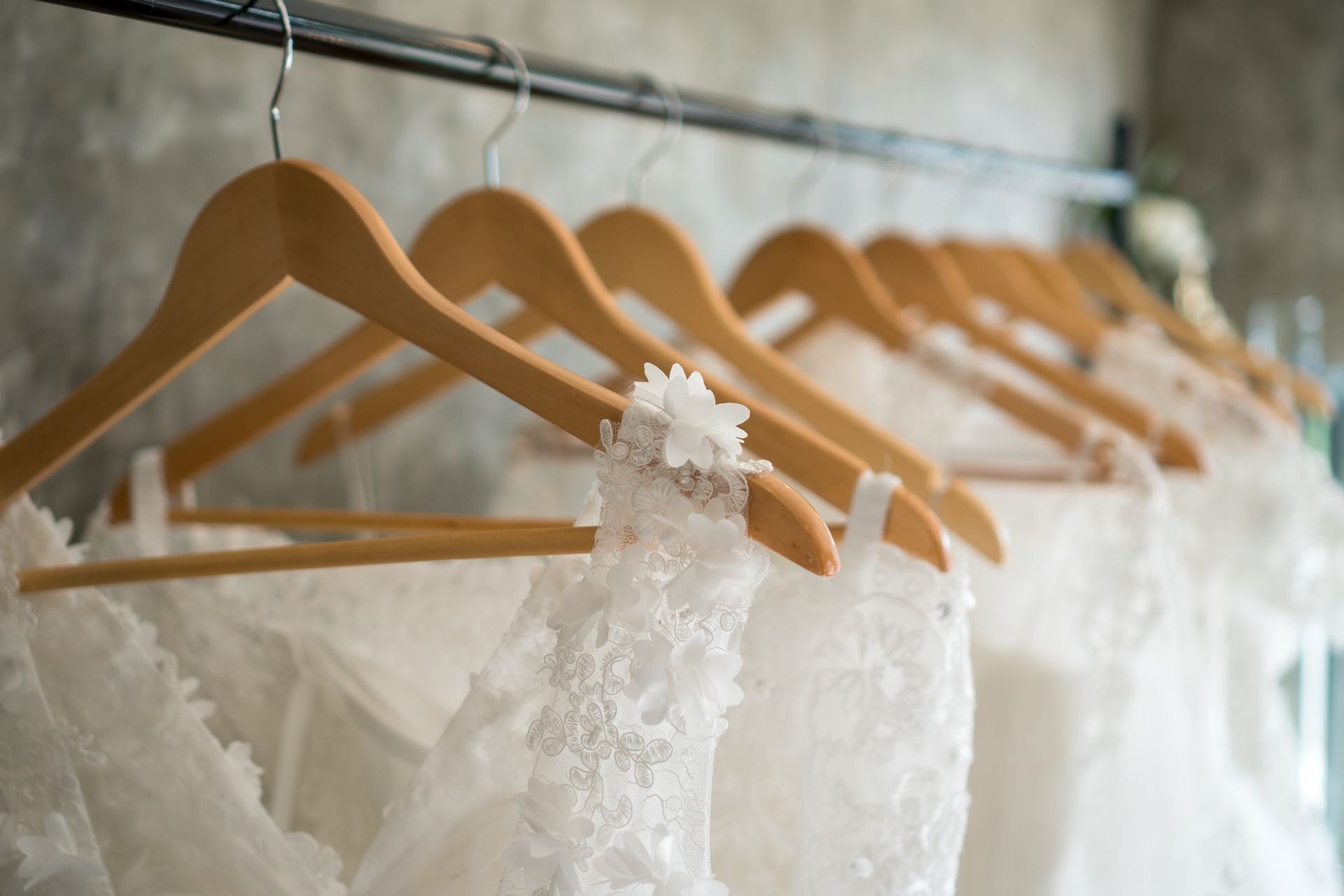 White bridal gowns hanging on wooden hangers in boutique