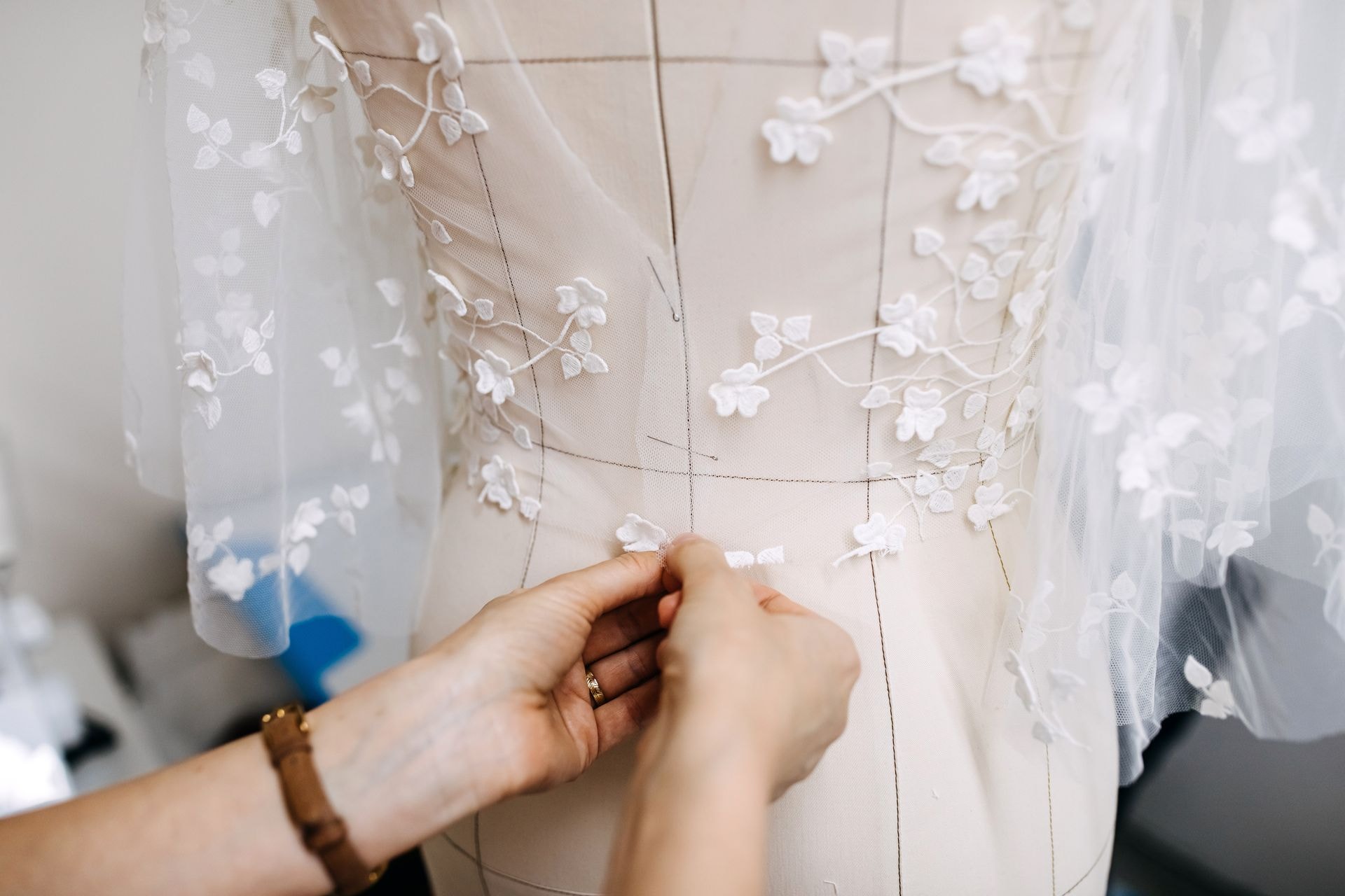 Hands working on lace detailing of a formal gown