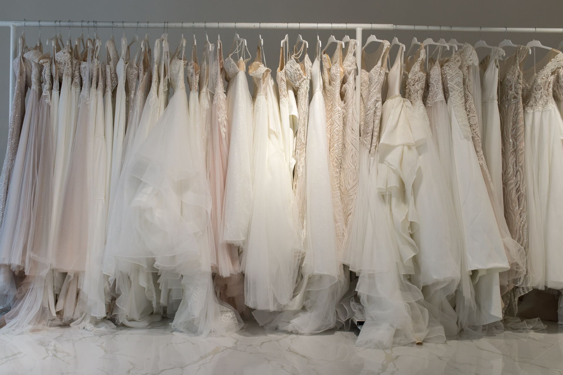 White wedding dresses hanging on wooden hangers in the boutique