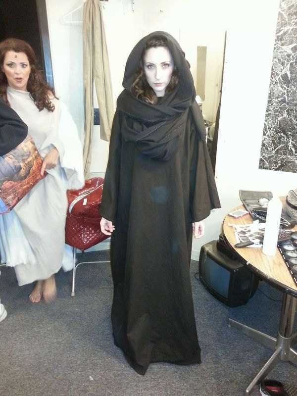 Women trying on medieval cloaks indoors