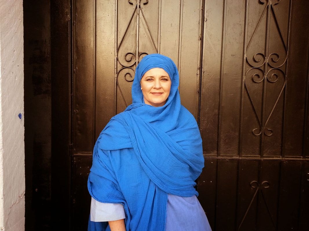 Woman wearing blue headscarf at ornate door