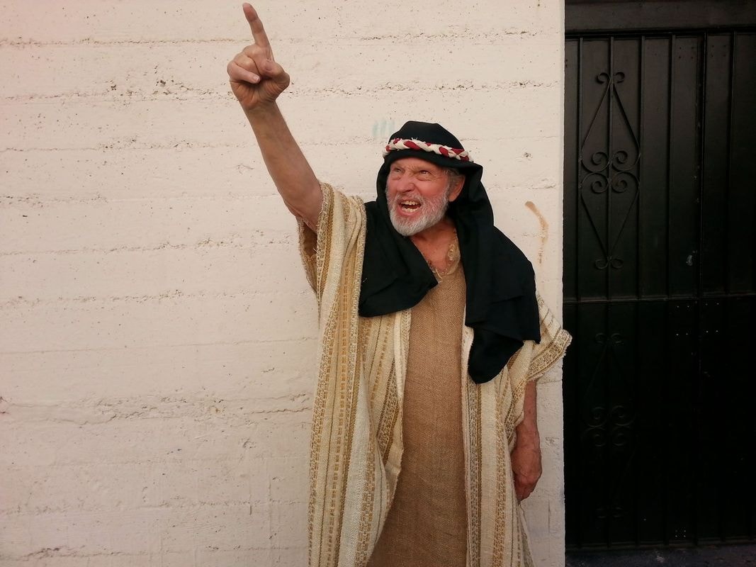 Man in traditional robes pointing upward joyfully
