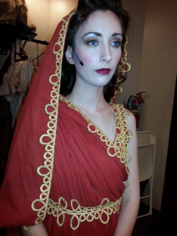 Woman wearing red draped gown with gold trim